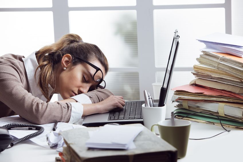 Tired businesswoman sleeping on the desk, in front of the computer screen.