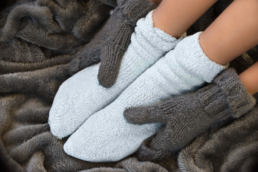 Feet in woolen socks, hands with wool gloves, on a blanket, 